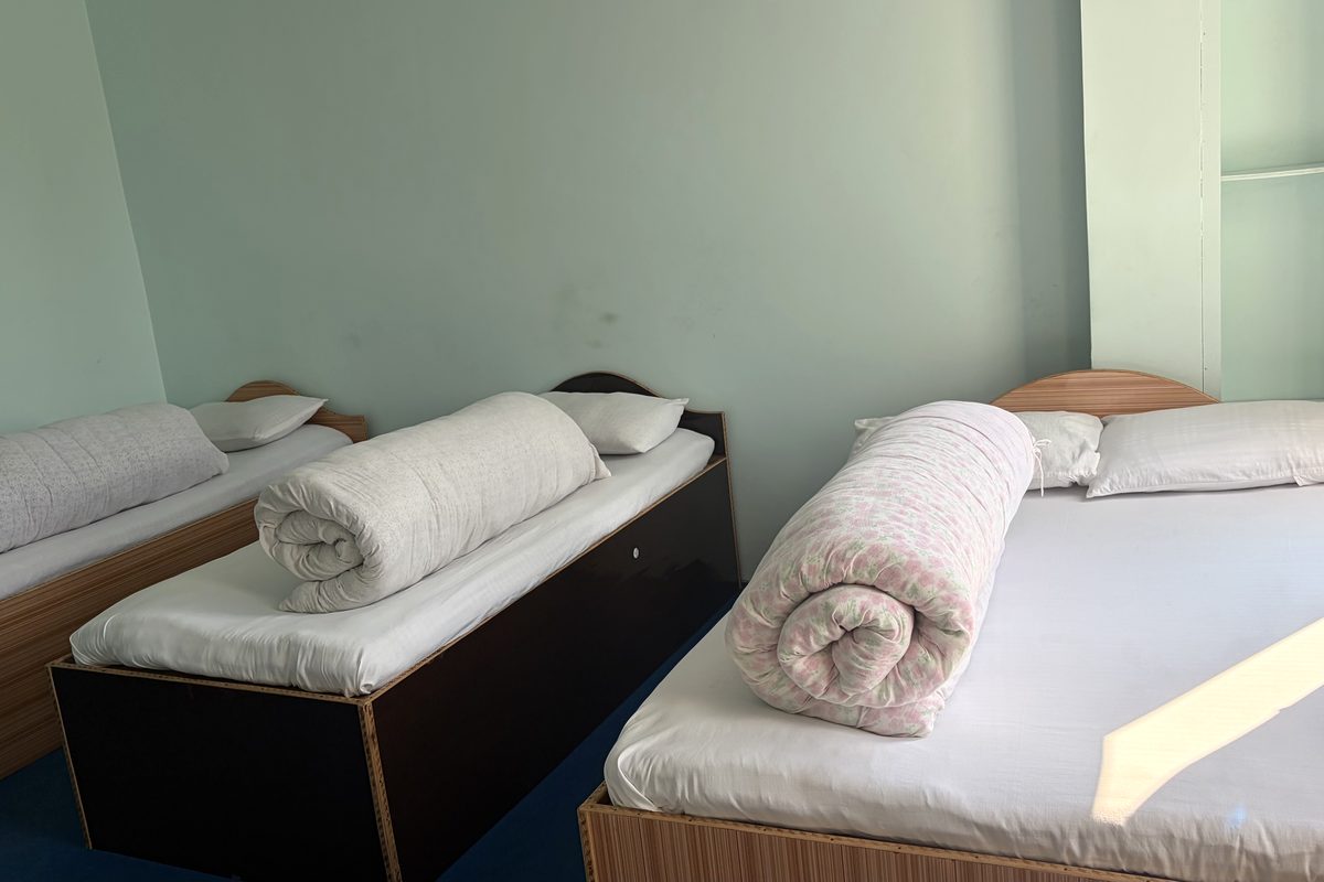 A guest room at Api Hotel with three beds, pillows and rolled quilts